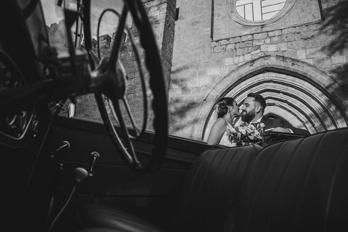 Recién casados mirándose junto coche de bodas arco iglesia Boda Monasterio de Valbuena